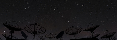 Silhouette satellite dish antenna on top of the building in urban area at night, with stars on clear skyの写真素材