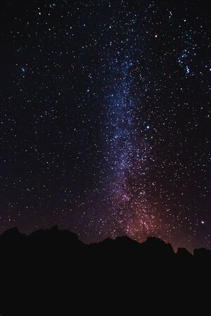 Silhouette mountain peak at night with sky full of stars and milky wayの写真素材