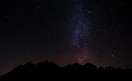 Silhouette mountain peak at night with sky full of stars and milky way