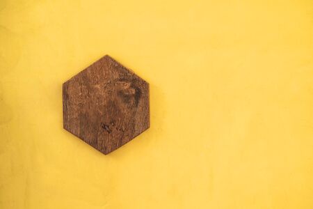 Hexagon wooden plate on yellow wall backgroundsの写真素材