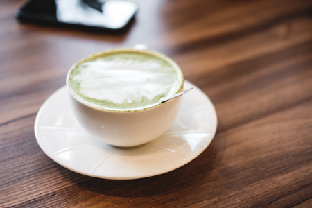 Soft focus hot matcha green tea latte, on wooden table