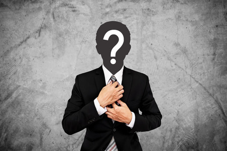 Businessman with question mark on head, on concrete wall backgroundの写真素材
