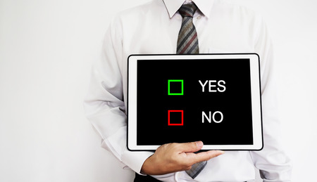 Business employee holding digital tablet with YES or NO choices selection on screenの写真素材