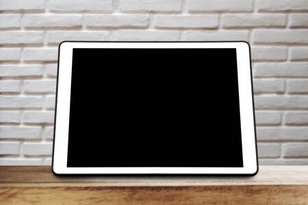 Digital tablet on wood table with white bricks backgroundの写真素材