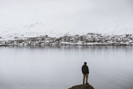a man standing on rock with view of the Akereyri city, Iceland in winterの写真素材