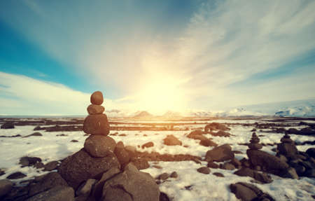 Stone stacked balance in winter landscape, with bright sunlightの写真素材