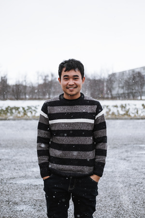 a man in sweater standing in snowy day in winter, with smiling faceの写真素材