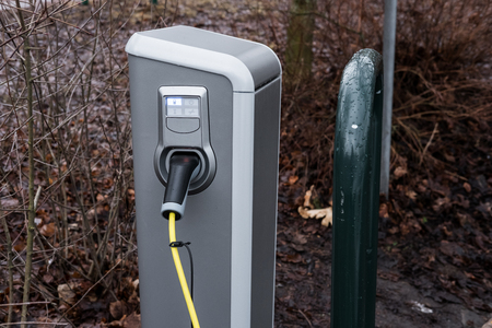 Charging an electric car with the power cable supply plugged-in station in public parkの写真素材
