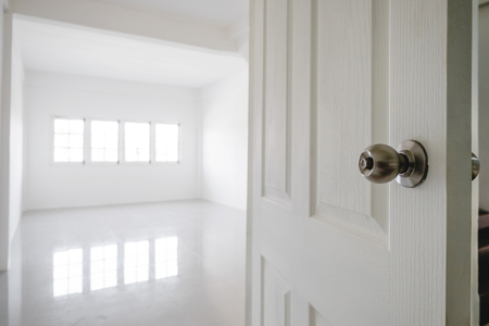 Close-up opened door with empty white room space, and bright light from windowの写真素材