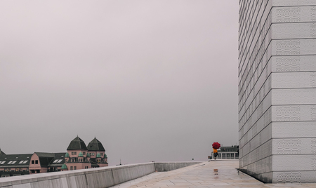modern buildings with a person in colorful rain suit and umbrella in rainy dayの写真素材