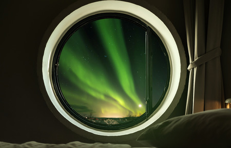 Interior circle window in bedroom with beautiful Northern lights (Aurora Borealis) view at nightの写真素材