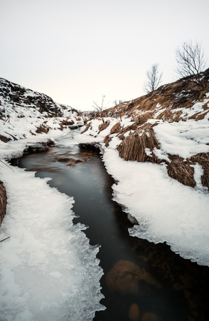 Vertical winter frozen river flowing landscapedの写真素材