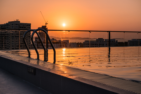 Swimming pool with stair on rooftop in the city in summer sunsetの写真素材