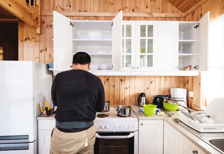 Rear view a man preparing breakfast in kitchen, in the morningの写真素材