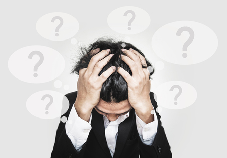 Businessman touching his head, with question marks sign on speech bubbles. doubt, problems, syndrome and disorder conceptsの写真素材