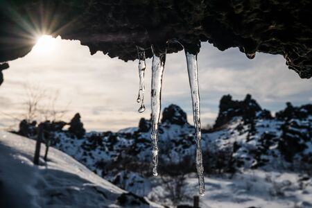 Frozen dripping water on the stone ceiling with bright sunlight in winterの写真素材