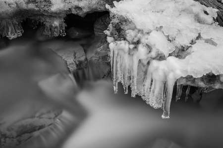 Long exposure creek water flowing with frozen dripping water, natural winterの写真素材