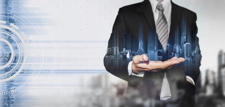 Businessman holding blue hologram of modern buildings, innovation technology conceptの写真素材