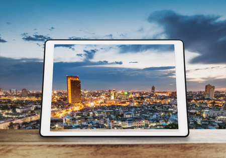 Digital tablet,  on wooden table with cityscape viewの写真素材