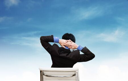 Businessman stretching arm  with blue sky and white clouds backgroundの写真素材
