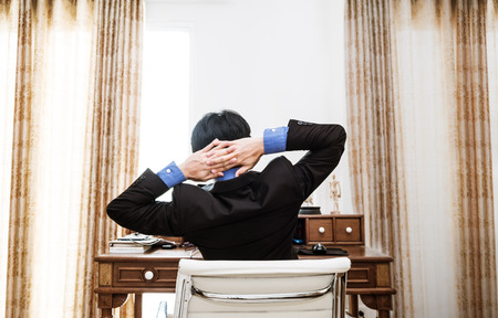 Rear view Businessman Stretching Arm to Relaxing while working in work placeの写真素材