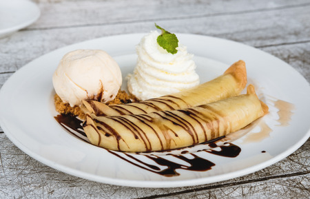 Banana crepes with vanilla ice cream and home made whip creme, glaze with chocolate and honey , selective focusの写真素材