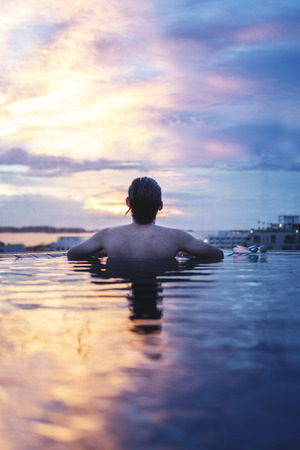 a man relax in the water under sunset sky in summerの写真素材