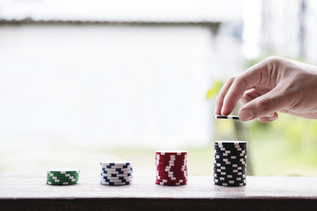 Hand putting gambling coin chips, with increasingの写真素材