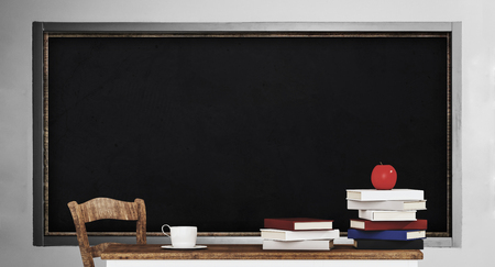 Blackboard, table, pile of books and apple, in classroomの写真素材