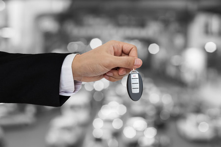 Hand holding car key remote with Bokeh of car traffic backgroundの写真素材