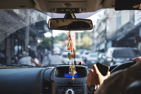 Modern car interior with hanging amulets charm on rear view mirror, driving on the road, selective focusの写真素材