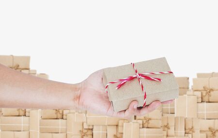 Hand holding, giving parcel box, with pile of boxes backgroundの写真素材