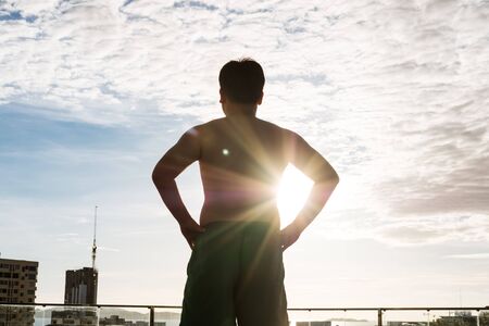 a man standing against sun, with sun flare through his armの写真素材