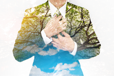 Double Exposure, Businessman in Suit with Big Tree and Bright Sunlight, with blue sky and white cloudsの写真素材