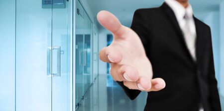 Businessman stretching out hand with blue modern office background, business welcome, greeting sign...