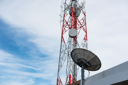 Telecommunication tower with satellite dish, on blue skyの写真素材