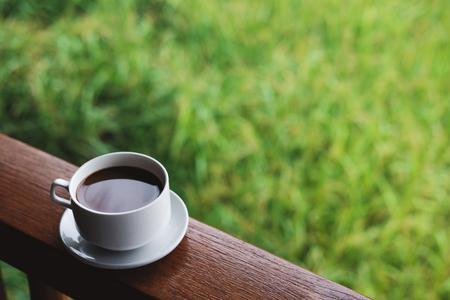 Coffee cup with saucer, on wood panel with defocus green grass lawn backgroundの写真素材