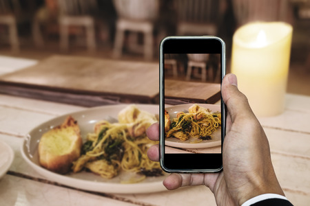 Taking food photo, dinner food photography by smart phone, seafood spaghetti under candle lightsの写真素材