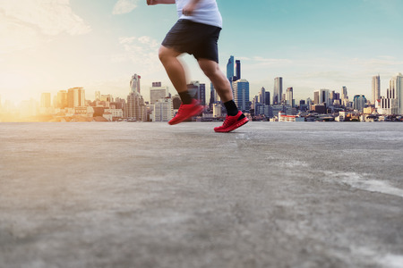 A Man Running on concrete road with city view in sunrise, selective focusの写真素材