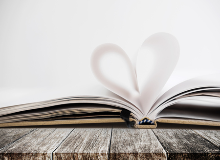 Heart shape in opened notebook page, on wooden tableの写真素材