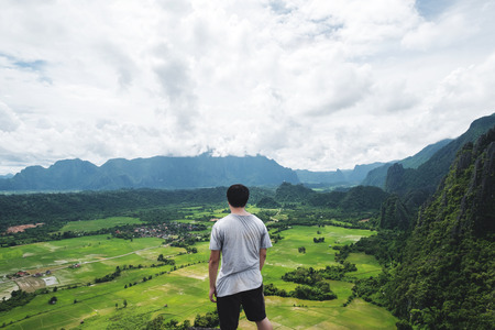 a man standing on mountain peak, traveling in tropical countryside, Vang Vieng in Laosの写真素材