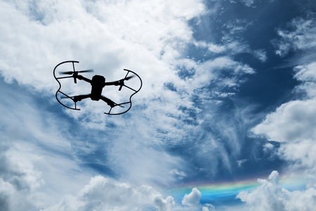 Silhouette drone flying on blue sky with rainbowの写真素材
