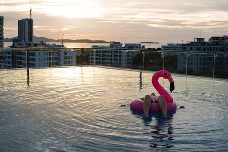 a man chilling on swim pool float, on swimming pool in sunset, in Pattaya city, Thailandの写真素材