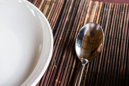Close-up spoon and white dish on wooden table matの写真素材
