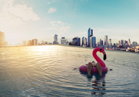 a man chilling on pink swim float, on swimming pool in sunriseの写真素材