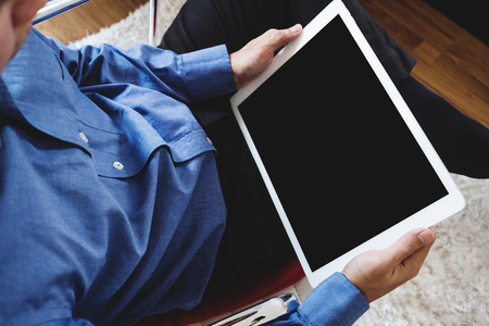a man using digital tablet computer, sitting on modern chair, clipping path empty black screenの写真素材