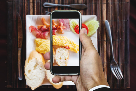 Taking food photography of homemade pan eggs fried and toasted bread, top view by smart phoneの写真素材