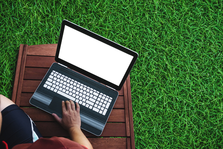a man using computer laptop on wooden chair with grass floor. Clipping path computer screenの写真素材