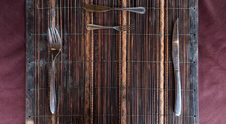 Top view, wooden mat with fork, spoon and knife on dining tableの写真素材