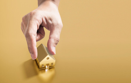 Hand picking golden house, real estate investment conceptの写真素材